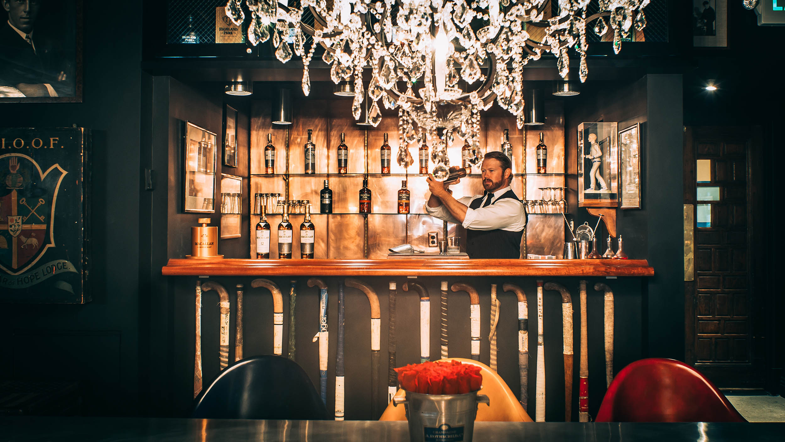 Los Angeles Athletic Club Blue Room; LA bartender standing behind a bar counter, holding a bottle of wine.